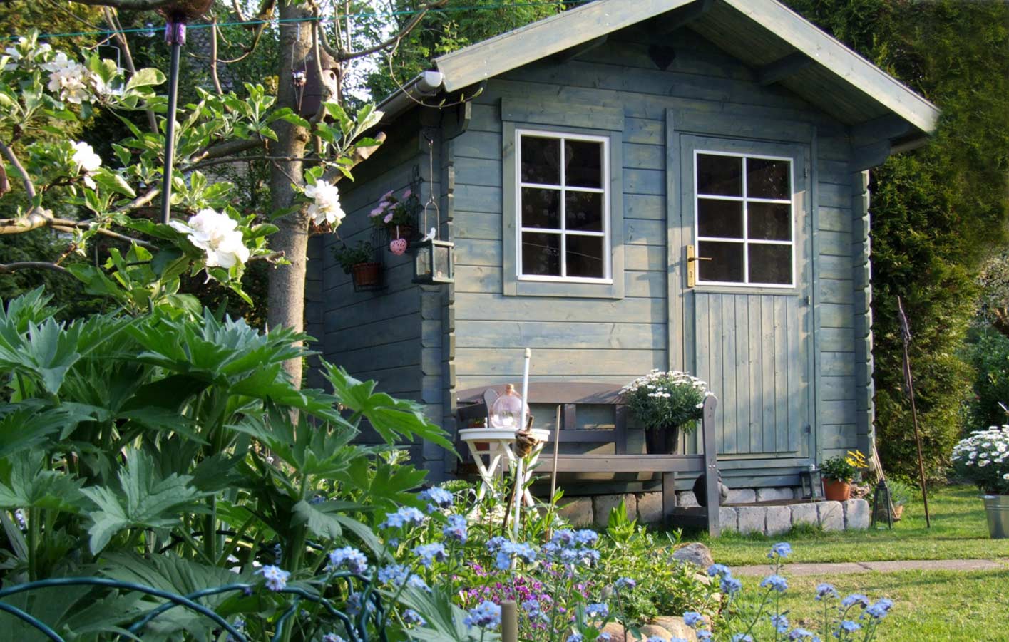 Gartenhaus aus Holz in einem grünen Garten.