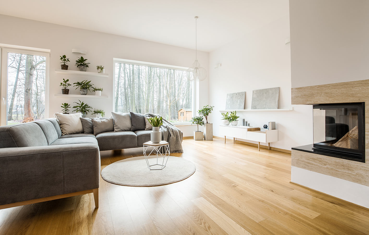 heller Furnierboden in einem Wohnzimmer mit grauer Couch und einem Kamin.